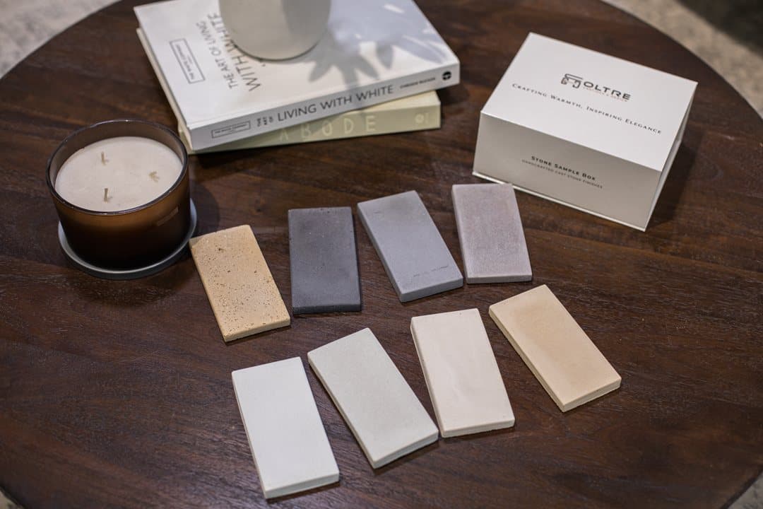 Oltre stone sample box with eight cast stone finish samples on a walnut table