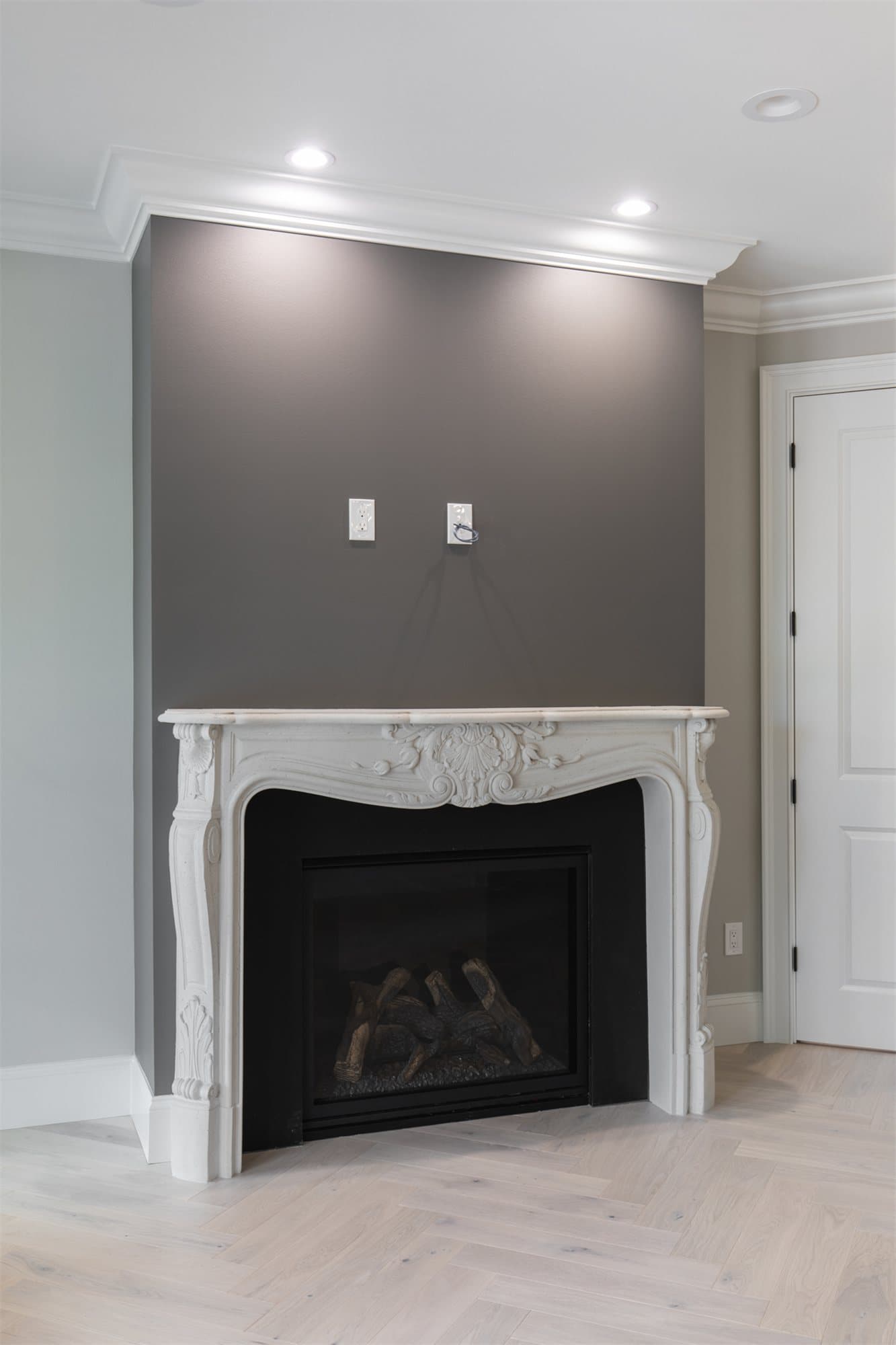 Louis XV cast stone surround with a carved French profile against a charcoal accent wall